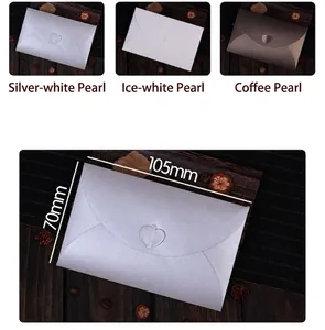 Detail of pearlescent paper envelopes with heart closures in silver, white, and coffee colors