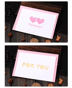 Detail of pink hollow-out Valentine card with Forever and For You text on wooden desk