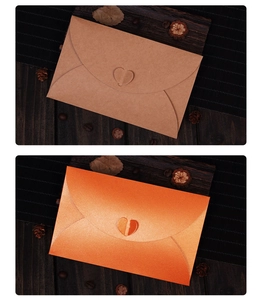 Detail of kraft and orange pearlescent envelopes with a creative heart-shaped paper clasp