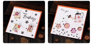 Detail of laser-cut Happy Birthday and floral greeting cards with orange border on wood