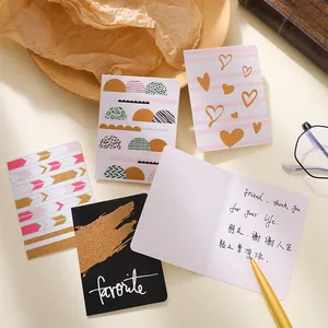 Assorted gold foil greeting cards with minimalist geometric patterns on warm background