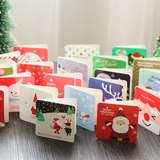 Detail view of mini Merry Christmas cards with festive illustrations on a wooden surface