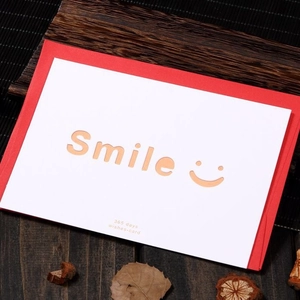 Minimalist hollow Smile greeting card set with red envelope on a rustic wooden desk