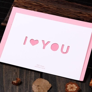 Hollow heart I LOVE YOU greeting card with pink envelope on a wooden desk