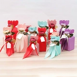 Colorful floral favor boxes with silk ribbons and blank gift tags on wooden background