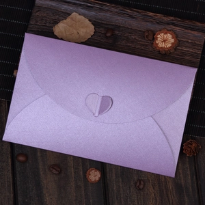Elegant purple pearlescent paper envelope with heart-shaped clasp on wood background
