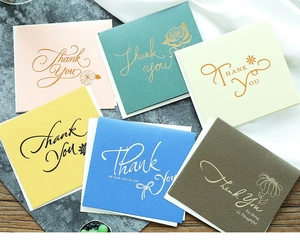Macro detail of textured pearl paper thank you cards with gold foil botanical designs