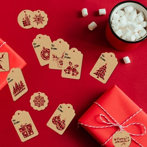 Detail of buffalo plaid Christmas gift tags with various shapes on red gift box