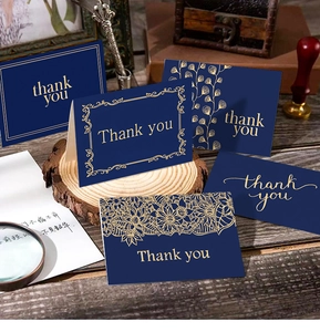 Macro view of navy blue thank you cards featuring gold foil stamping and vintage patterns