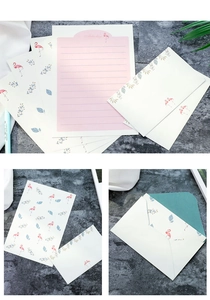 Detail of flamingo stationery set with pink lined paper and floral envelopes on stone texture