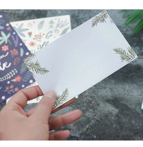 Detail shot of a minimalist greeting card featuring green pine needle prints on white paper