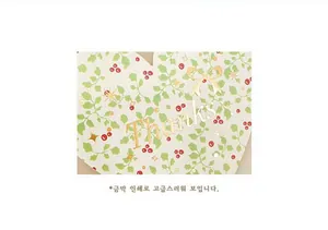 Detail of gold foil Thanks text with green leaves and red berries on a gift card
