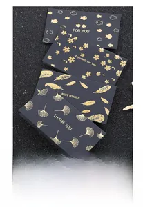 Detail of black matte greeting card featuring premium gold foil feather and leaf patterns