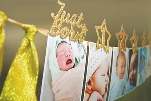 Detail of glittery gold Just Born banner with star cards and clips for baby photos