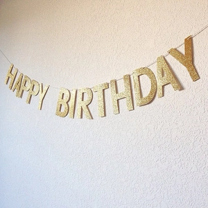 Golden glitter Happy Birthday banner sign hanging on a white textured background wall