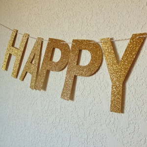 Glittering gold Happy Birthday banner showing the detailed HAPPY letter cutout on a string