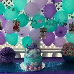 Detail of Mermaid theme birthday party set with glitter banners and sea animal cake decor