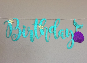 Detail of glitter mermaid birthday banner with teal lettering and shell decorations