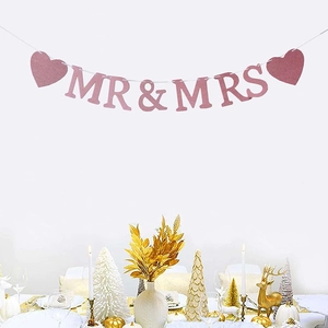 Striscione MR & MRS rosa glitterato con cuori appeso su un tavolo festivo