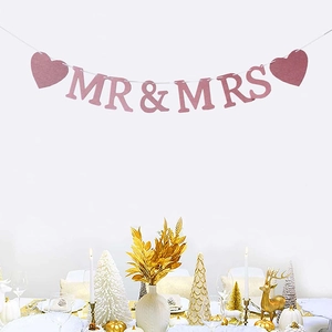 Striscione nuziale Mr & Mrs rosa glitterato con cuori sopra un tavolo da ricevimento bianco