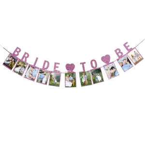Close-up of glittery pink Bride To Be banner with heart accents and photo holders