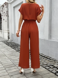 Rear view of elegant brick red short sleeve jumpsuit with high waist tie and wide legs