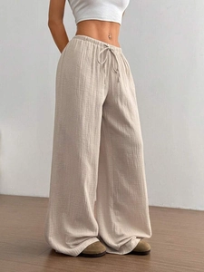 Detail von Kordelzug am Gummibund und natürlicher Faltenstruktur der beigen weiten Hose