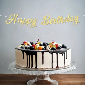 Glittering gold Happy Birthday banner hanging above a chocolate cake for party decor
