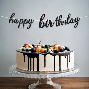 Glittery black Happy Birthday banner hanging over a cake for party decoration