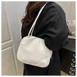 Minimalist white cloud-shaped shoulder bag in PU leather worn by a model in a modern room