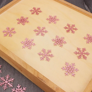 Pink glitter snowflake confetti decorations on wooden tray for Christmas party table decor