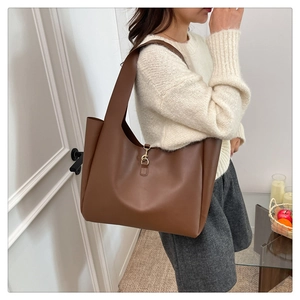 Detail of soft brown leather tote bag with gold metal buckle and wide shoulder strap