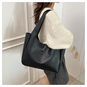 Detail of a black large tote bag with a gold metal hook on soft matte synthetic leather