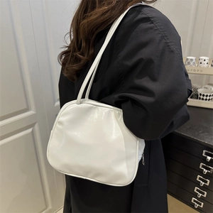 Minimalist white PU leather shoulder bag worn by model in a cozy indoor setting