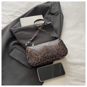Detailed view of leopard print underarm bag next to a phone for size comparison