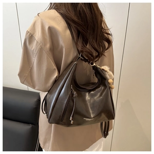 Close-up of a large coffee-brown leather tote bag worn by a model in a minimal setting