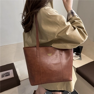 Classic vintage brown tote bag with gold lettering shown in a stylish urban setting