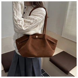 Dettaglio della borsa tote in pelle scamosciata marrone scuro con cinturini e tracolla sottile