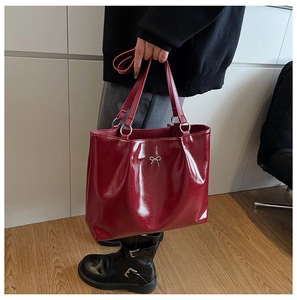Detail of red tote bag with shiny leather texture and silver bow metal ornament