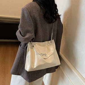 Sac bandoulière beige chic avec boucle nœud argentée et bandoulière chaîne sur modèle