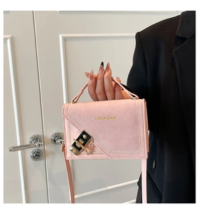 Detailed view of a pink suede crossbody bag with gold turn-lock and chain strap
