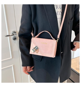 Detail of pink faux suede crossbody bag featuring gold clasp lock and fashion logo