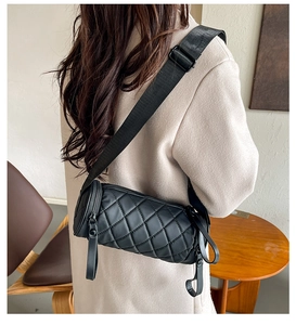 Detailed macro view of black quilted rhombus barrel bag with nylon strap and zipper