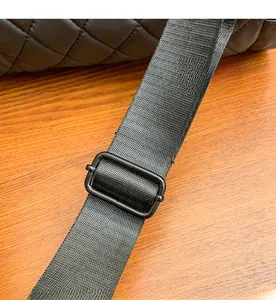 Detail of adjustable black nylon shoulder strap with matte metal buckle on quilted bag