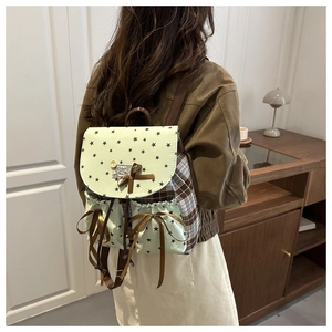 Detail of mint green canvas backpack featuring star prints and brown ribbon bow
