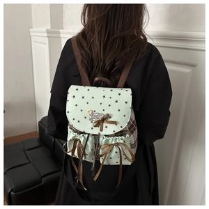 Close-up of mint green backpack with star prints and brown ribbon bows worn by a model