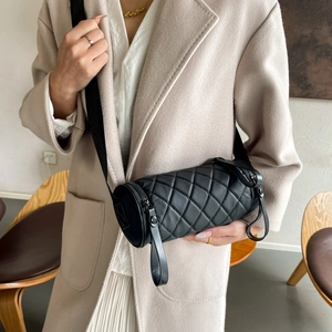 Detail of black quilted cylinder bag showing soft padded texture and minimalist shoulder strap