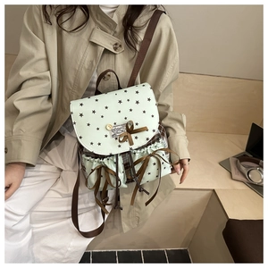 Detail of light green vintage backpack with star patterns and ribbon bow on model