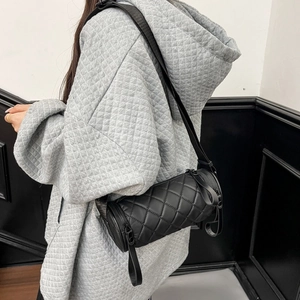 Close-up of quilted cylinder bag worn by model showing texture and nylon strap