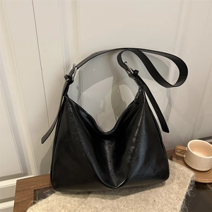 Minimalist black tote bag in oil-wax finish with wide adjustable strap and silver hardware